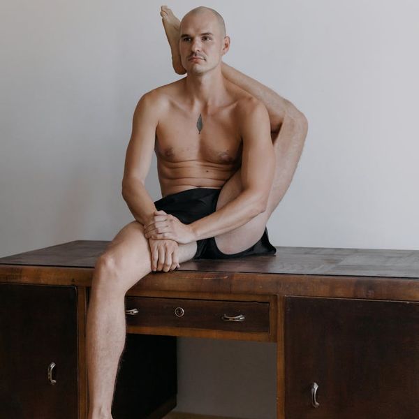 Man performing a controlled strength exercise in a dark, minimalist setting.